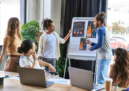 multicultural colleagues discussing startup project near flip chart with infographics in office